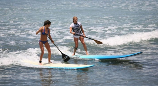 dos chicas cogiendo las olas practicando paddle surf.jpg